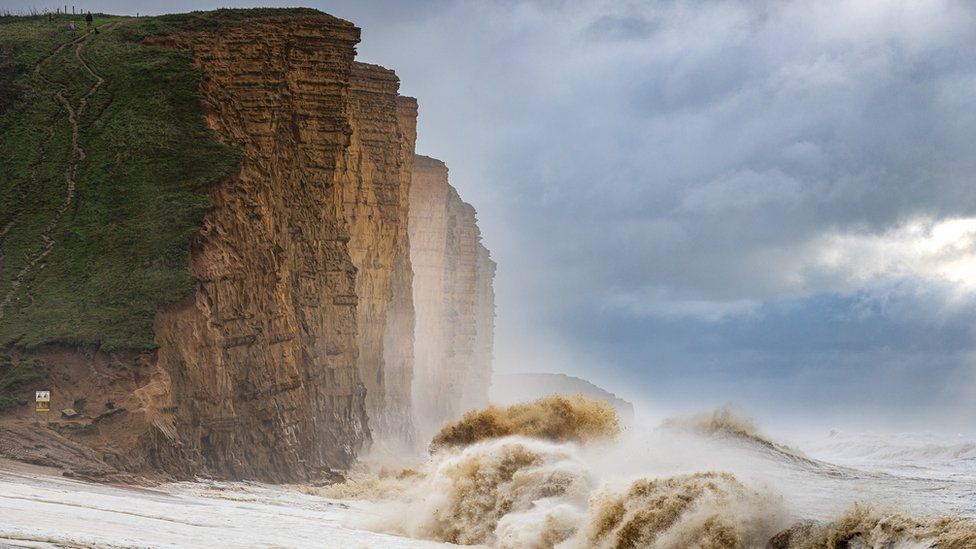 Waves crash against the cliffs at West Bay in Dorset