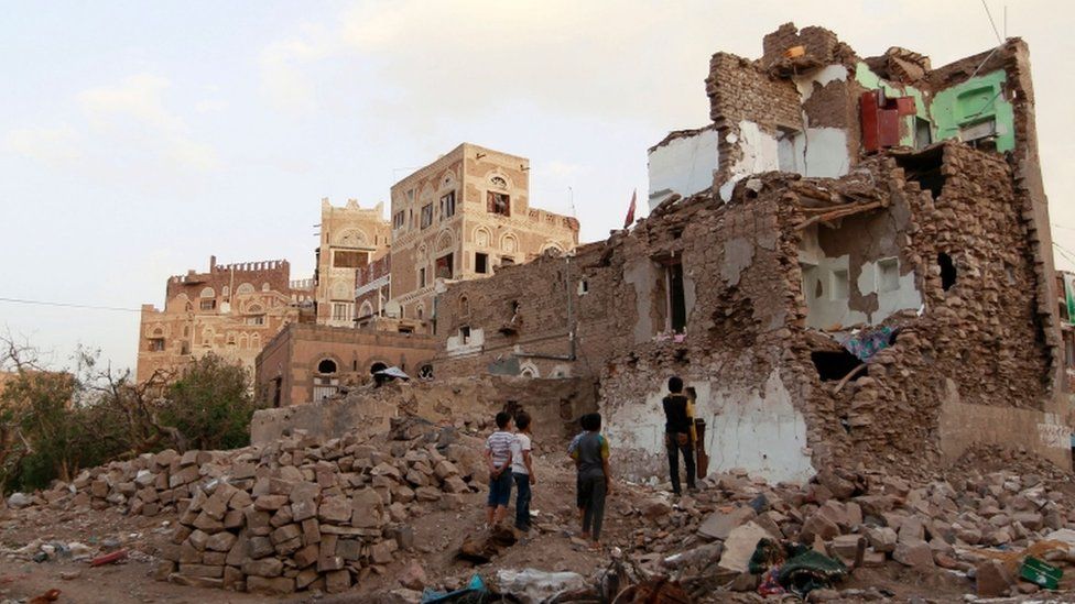 Yemeni children look at buildings that were damaged by air strikes carried out by the Saudi-led coalition on March 23, 2016