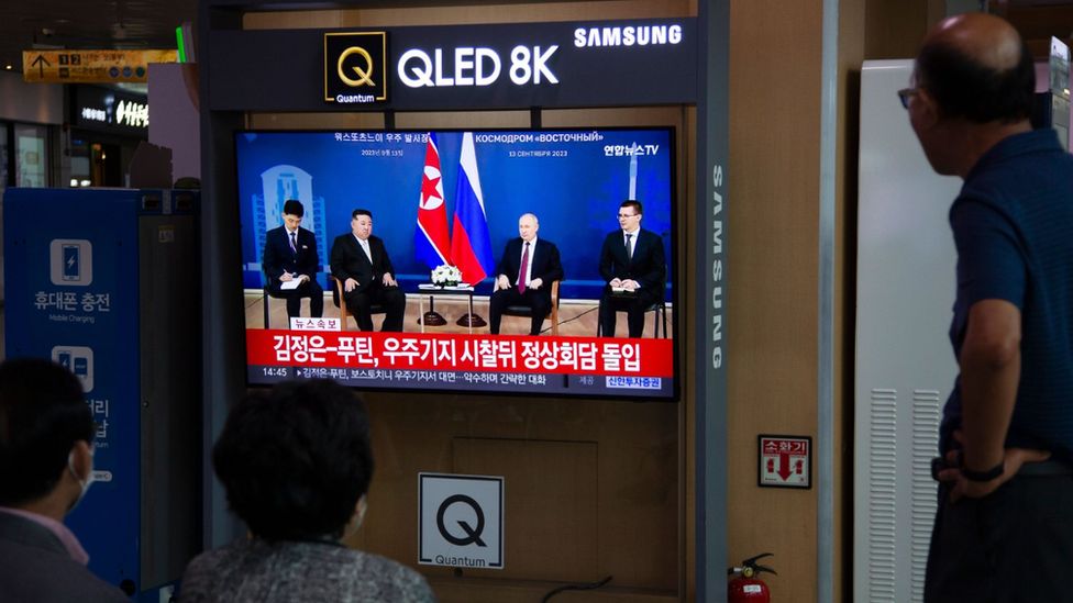 People at a train station in Seoul watch a news report showing Kim and Putin meeting