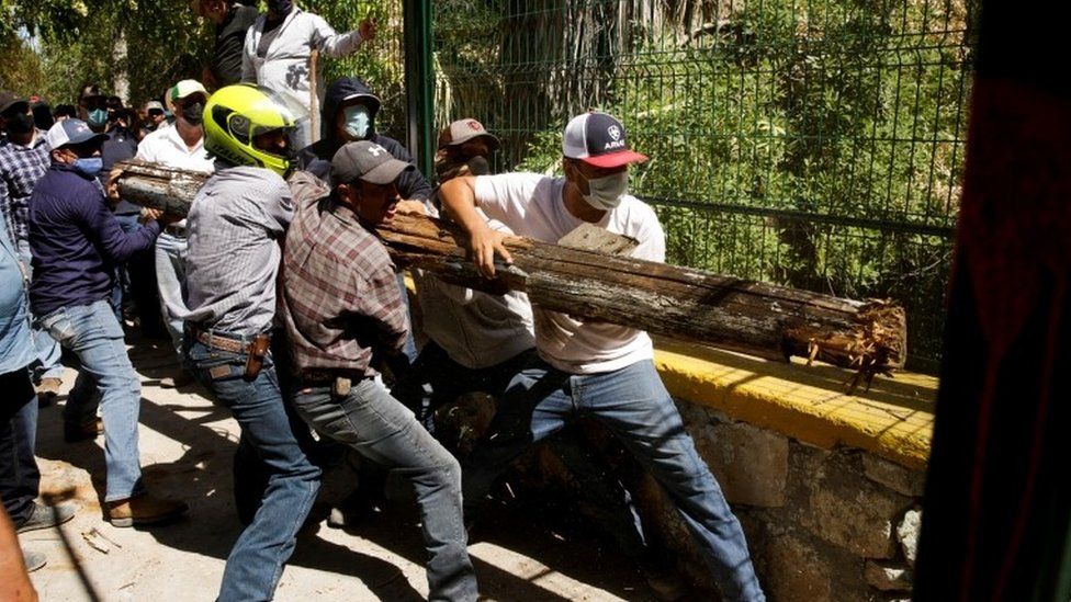 Farmers hold a wooden trunk as they try to open a door to enter La Boquilla dam during a protest