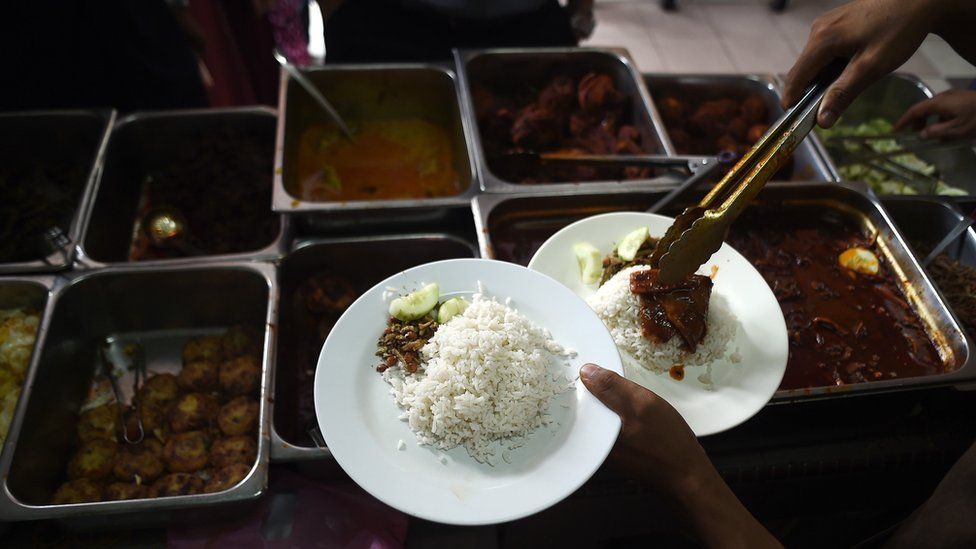 A stall assistant serves up nasi lemak in Kuala Lumpur