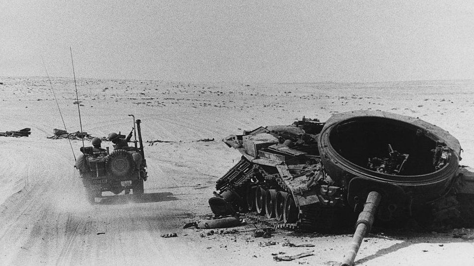 An Israeli tank driving past a destroyed tank in October 1973
