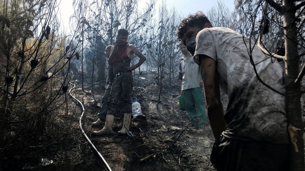 Men work to douse hotspots in an area hit by a wildfire in El Bir village, Bejaia province, Algeria August 16, 2021.
