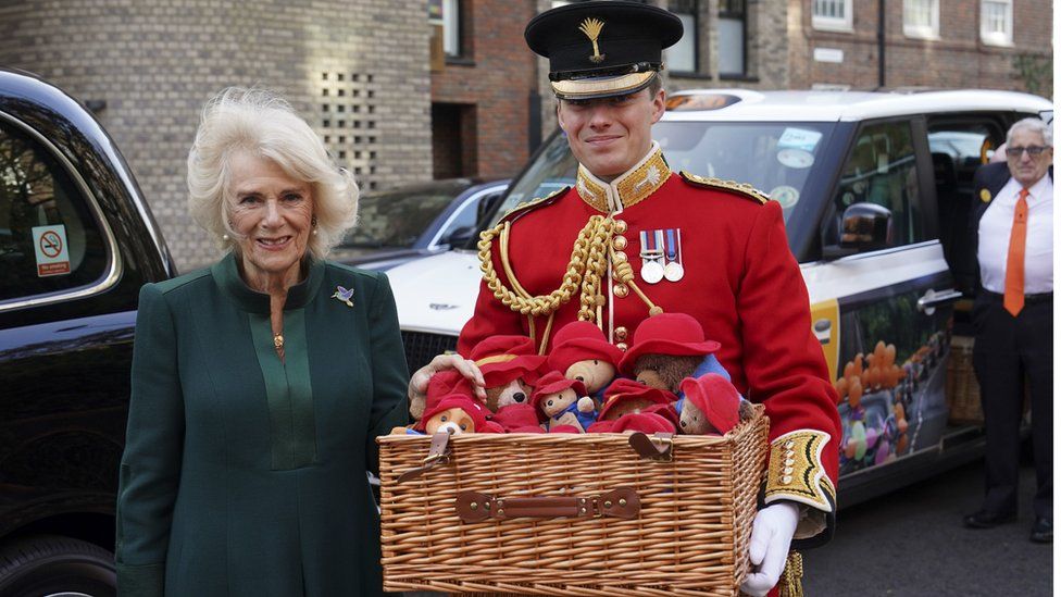 Camilla, her equerry carrying a basket full of Paddington Bears