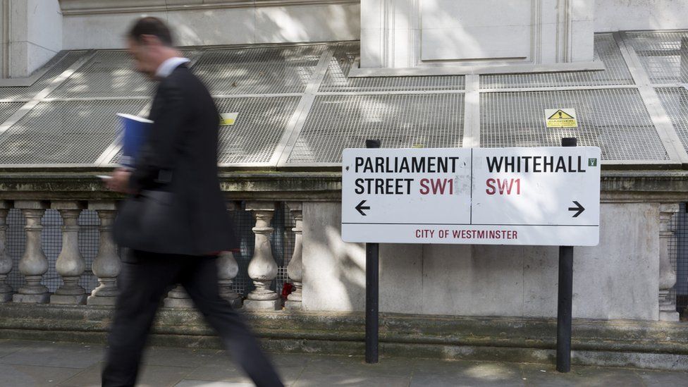 Man walking past Whitehall signs
