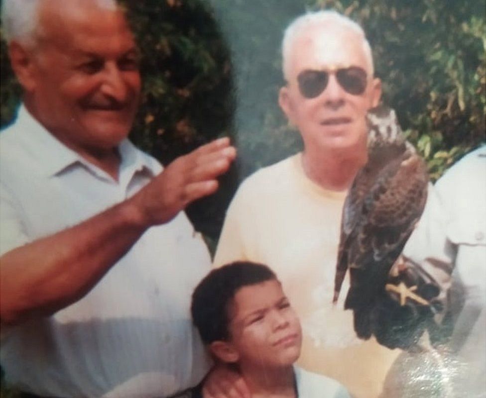 Two older men with a young boy looking at a bird