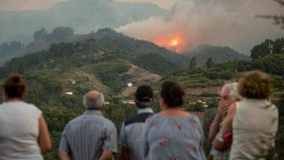 A crowd looks over a hilltop ablaze in Gran Canaria