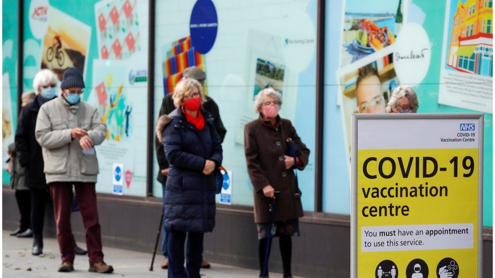People queue to receive the coronavirus vaccine outside a closed down Debenhams store that is being used as a vaccination centre in Folkestone, Kent