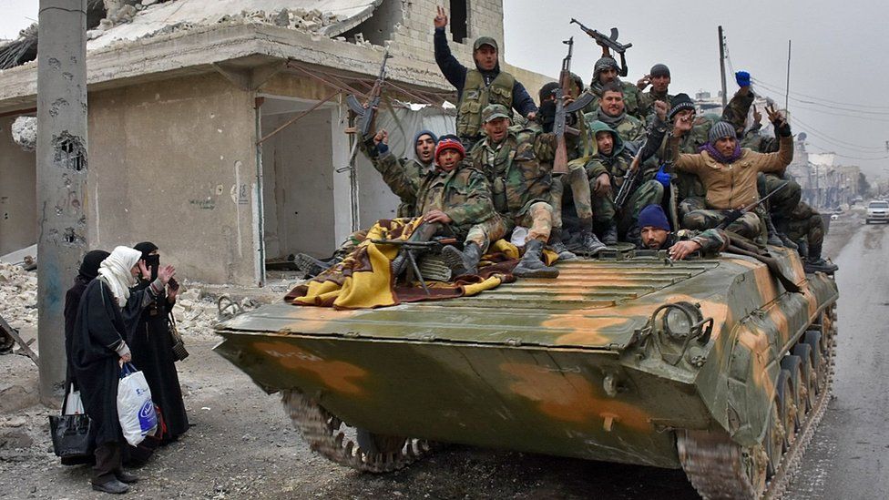 Syrian government forces ride through the Masaken Hanano district of Aleppo, on an armoured personnel carrier (30 November 2016)