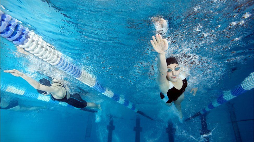 Two female swimmers in a pool, underwater