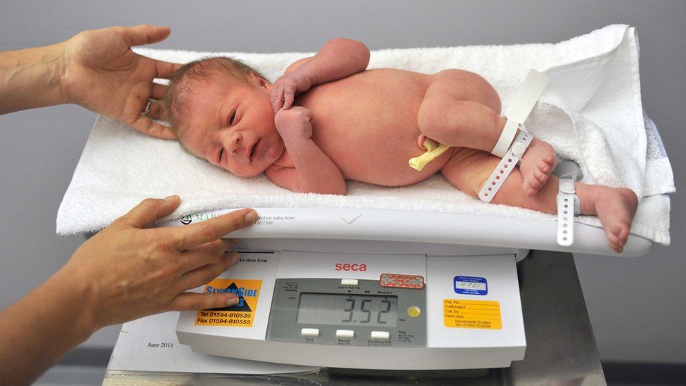 A newborn baby is weighed on scales