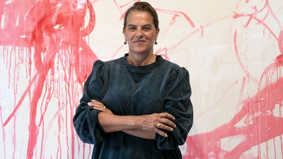 Tracey Emin standing in front of a large canvas showing a red and white artwork