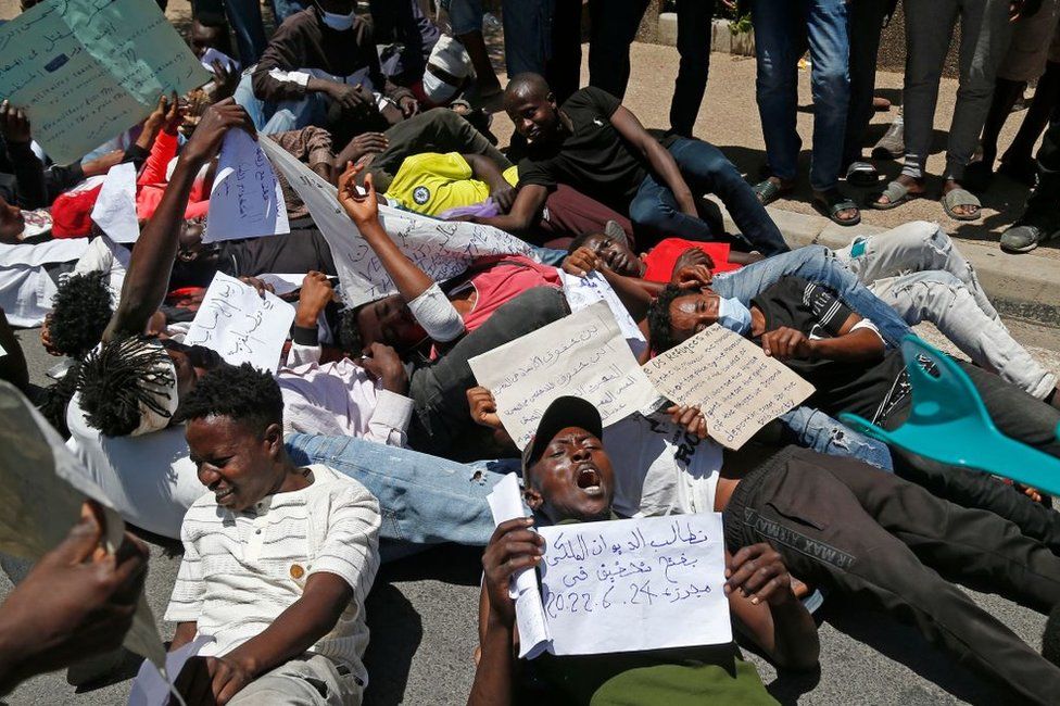 Migrants hold placards during an anti-racism demonstration in the Moroccan capital Rabat on June 28, 2022.
