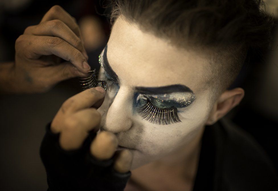 A make-up artist applies fake eyelashes to Elias