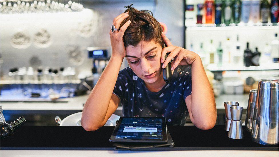 Woman on the phone behind a bar