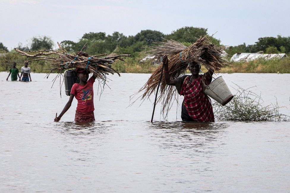 South Sudanese women walk in a flooded area that has been isolated for about a month and a half due to the heavy rain in Pibor Town