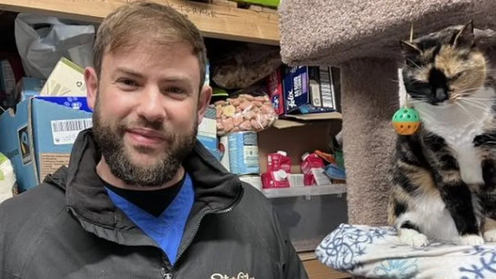 Jack Linnell from St Giles Animal Rescue Centre with Lily in their food bank storeroom