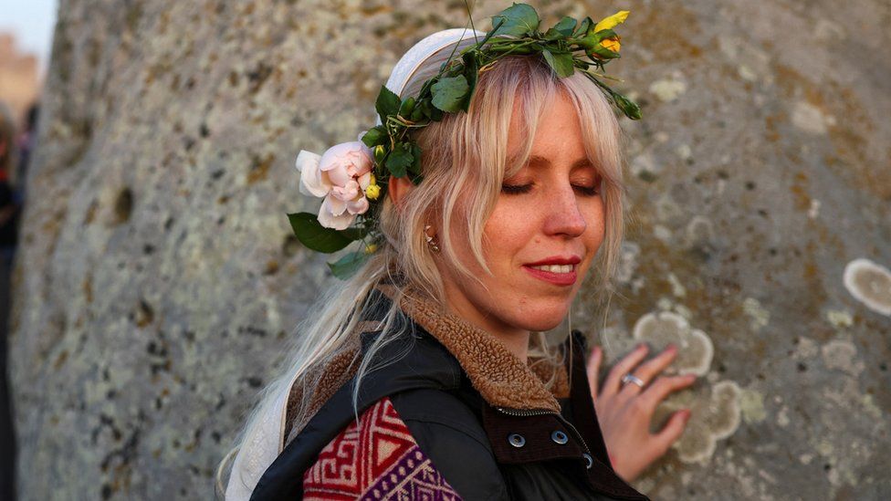 Woman wearing flower headpiece touching stone