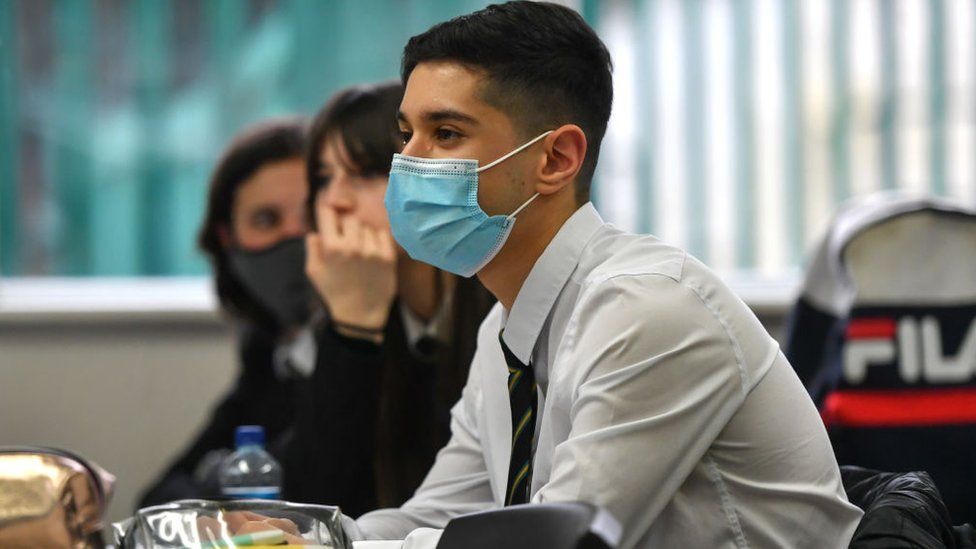 A teenage boy in a mask in a classroom