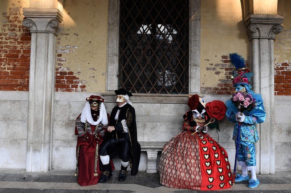 Masked revellers wearing traditional carnival costumes pose in Saint Mark's Square during Venice's Carnival