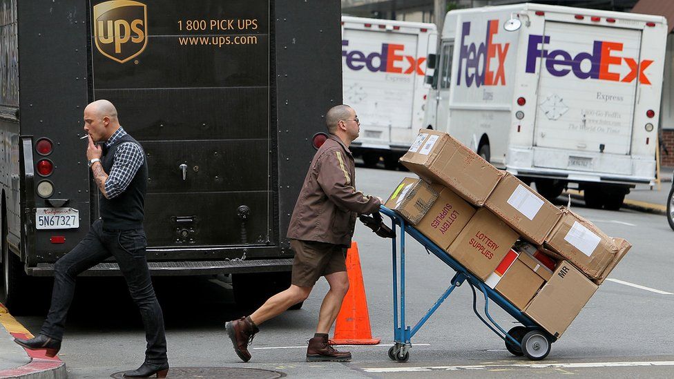 United Parcel Service (UPS) driver Grant Jung (R) pushes a handtruck loaded with boxes as he makes deliveries in San Francisco