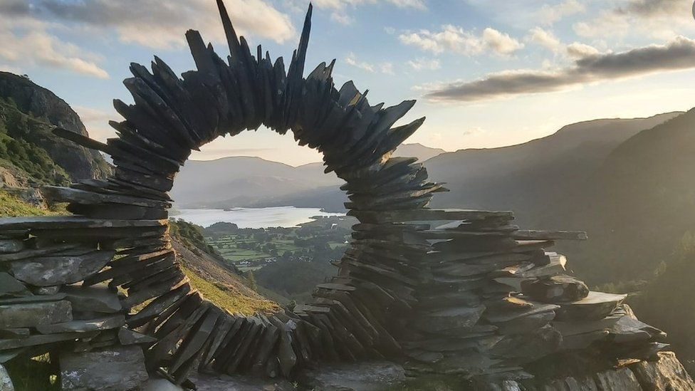 Slates piled together in a circle with a view of a lake visible through the middleLakeAKE