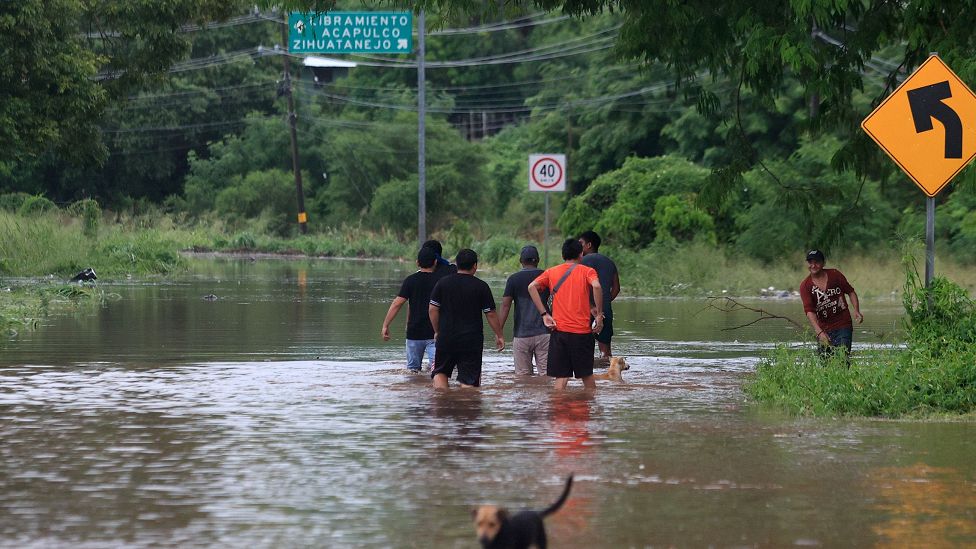 People walk in flooded area due to Tropical Storm Max in Tecpan de Galeana, Guerrero