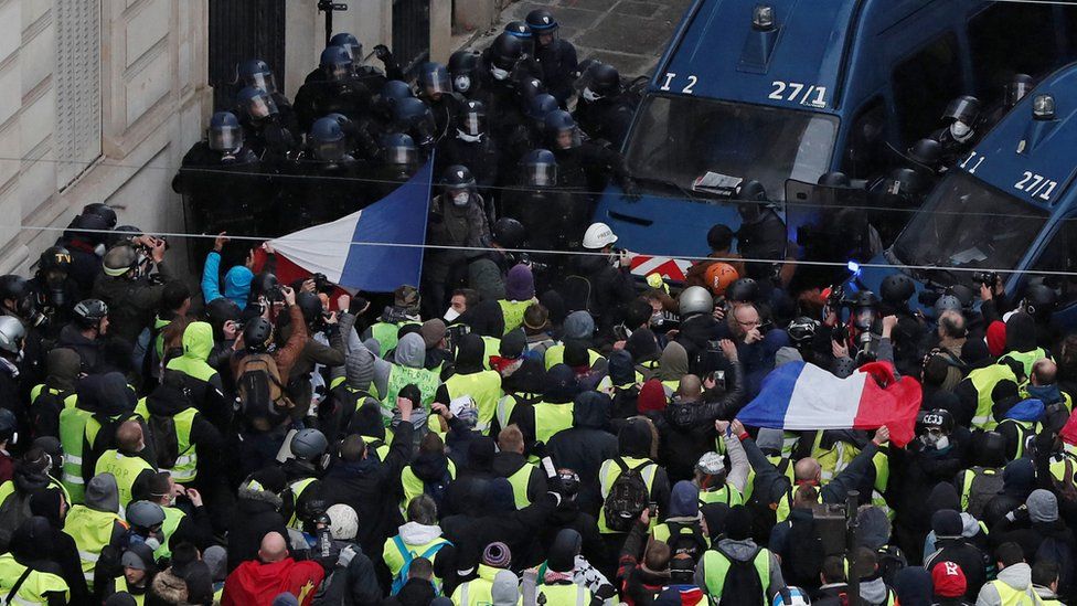 Hundreds of protesters surge towards a line of police officers in Paris