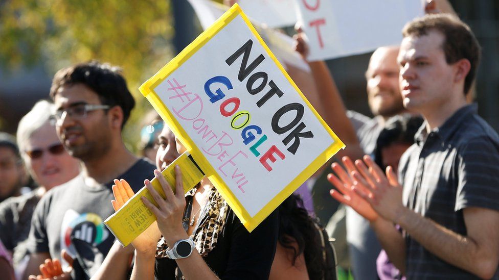 A Google employee (centre) holds a sign that reads "Not OK Google" during a walkout in Mountain View, California