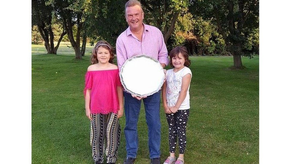 Tim Richardson seen here with a golf trophy standing next to his daughters, was a keen player before his back injury