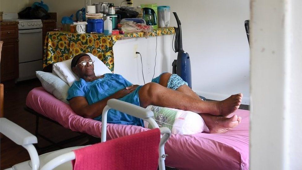 Mary Mitchell, 82, lays on a hospital bed in her room, without power, food or water at Cypress Run assisted living facility in Immokalee, Florida.