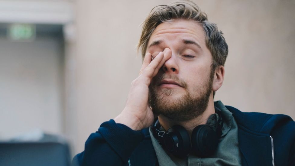 A man rubbing his eyes with tiredness