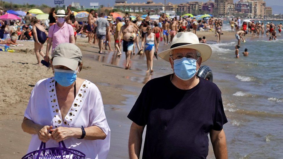 A couple wearing face masks on a beach in Valencia