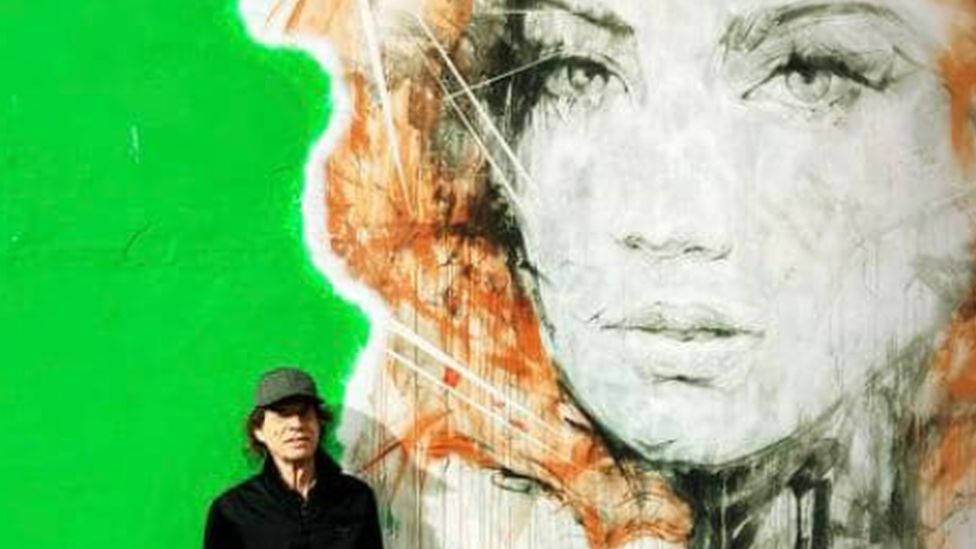 The legendary singer poses in front of street art