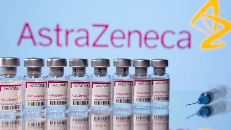 Vials labelled "Astra Zeneca COVID-19 Coronavirus Vaccine", and a syringe are seen in front of a displayed AstraZeneca logo. File photo