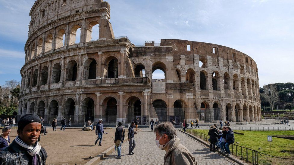 A tourist wears a face mask in front of the Colosseum in Rome, Italy
