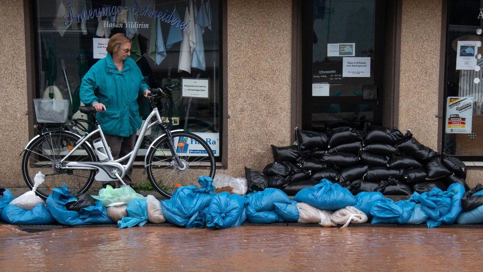 A woman looks at sandbags piled up in front of a shop and to protect against flood water in Erftstadt, Lechenich, western Germany, on July 16, 2021.