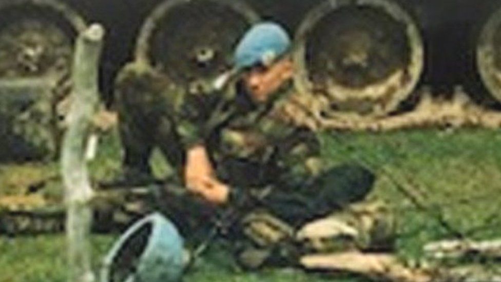 Shaun Pinner lying in front of a tank with UN written on the side