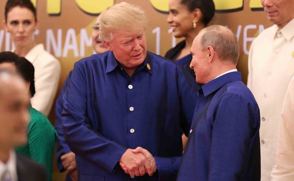 US President Donald Trump (L) shakes hands with Russia"s President Vladimir Putin (R) as they pose for a group photo