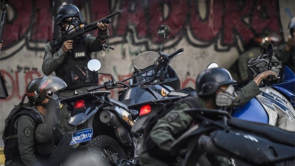 Venezuelan security forces take cover upon coming under fire during a confuse skirmish in Caracas on July 30, 2017