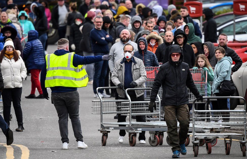 Members of the public queue to get into the Costco store in Glasgow, Scotland before opening on the morning of March 21, 2020, a day after the British government said it would help cover the wages of people hit by the coronavirus outbreak as it tightened restrictions to curb the spread of the disease.