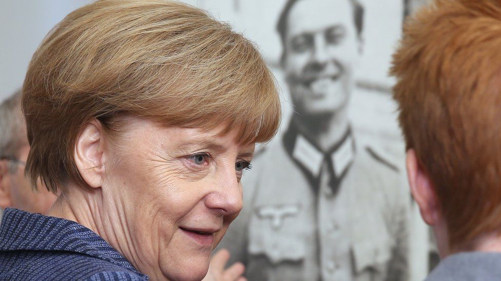 German Chancellor Angela Merkel stands next to a photo of anti-Nazi conspirator Claus von Stauffenberg while looking at exhibits at the newly-expanded museum of the German Resistance Memorial Center