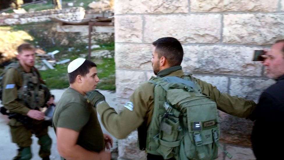 An Israeli soldier blocks an Israeli settler (2nd L) trying to get to Yasser Abu Markhiya (R), a Palestinian, in Hebron, in the occupied West Bank