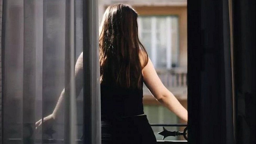 young woman front behind looking out window