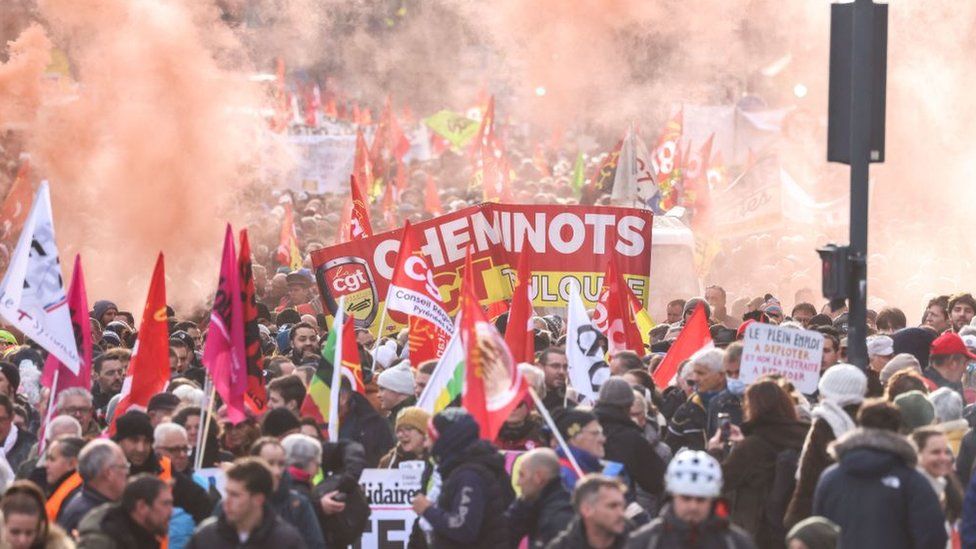 Protesters wave flags and banners during a rally called by French trade unions in Toulouse, southwestern France, on January 19, 2023. - A day of strikes and protests kicked off in France on January 19, 2023