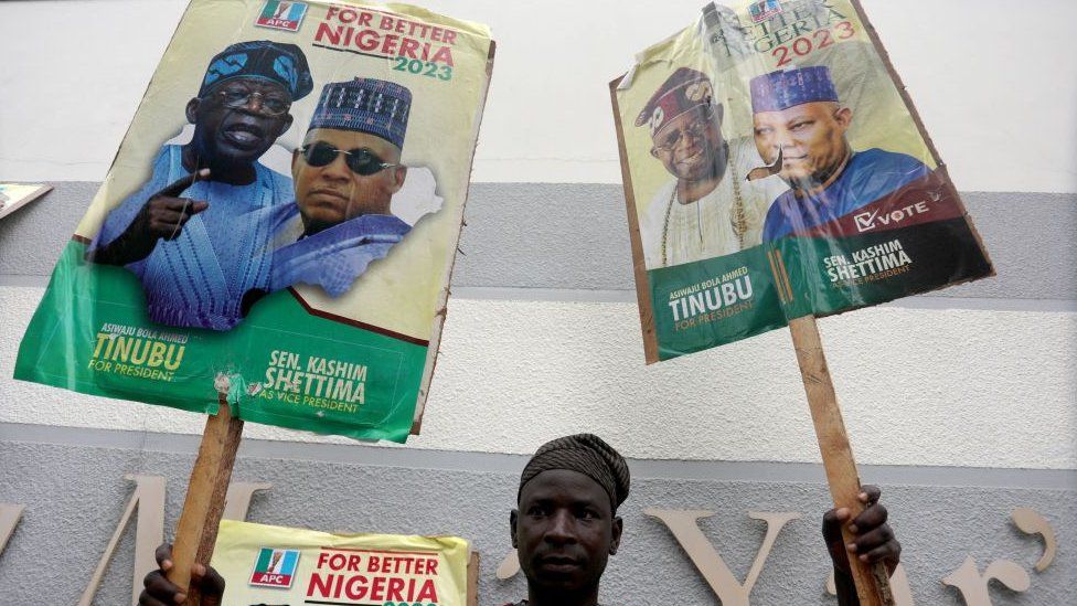 A man holders political posters with Bola Ahmed Tinubu and his running mate, Shettima, on them