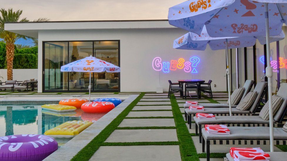 A poolside decorated with Guess merchandise and signage.