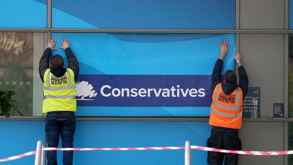 Workers put up Conservative posters on conference venue