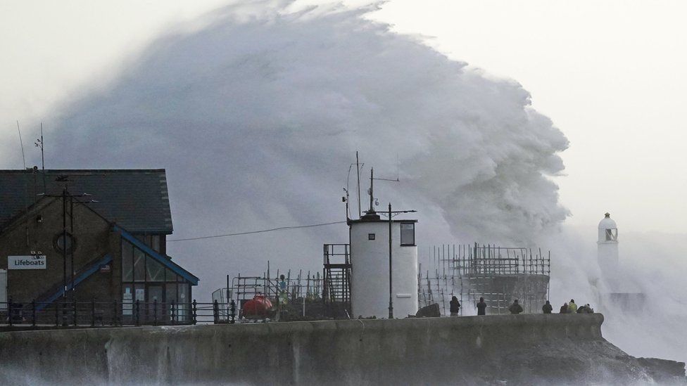 Waves crash against the sea wall and Porthcawl Lighthouse in Porthcawl, Bridgend, Wales