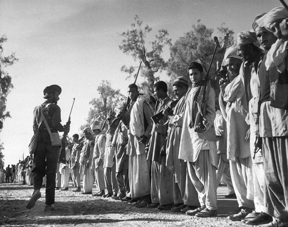 In this 1947 picture, armed Pathan tribesmen wait on the road between Peshawar and Rawalpindi for their leader Batcha Gul, of the Mohman tribe, to arrive with trucks and extra ammo, and lead them into battle in Kashmir.